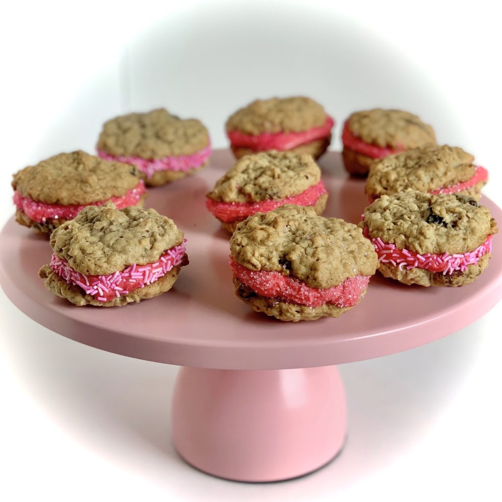 oatmeal raisin cookies with pink frosting displayed on pink cake stand