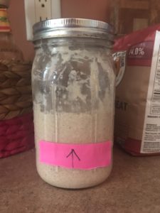 Sourdough starter with sticky note for growth